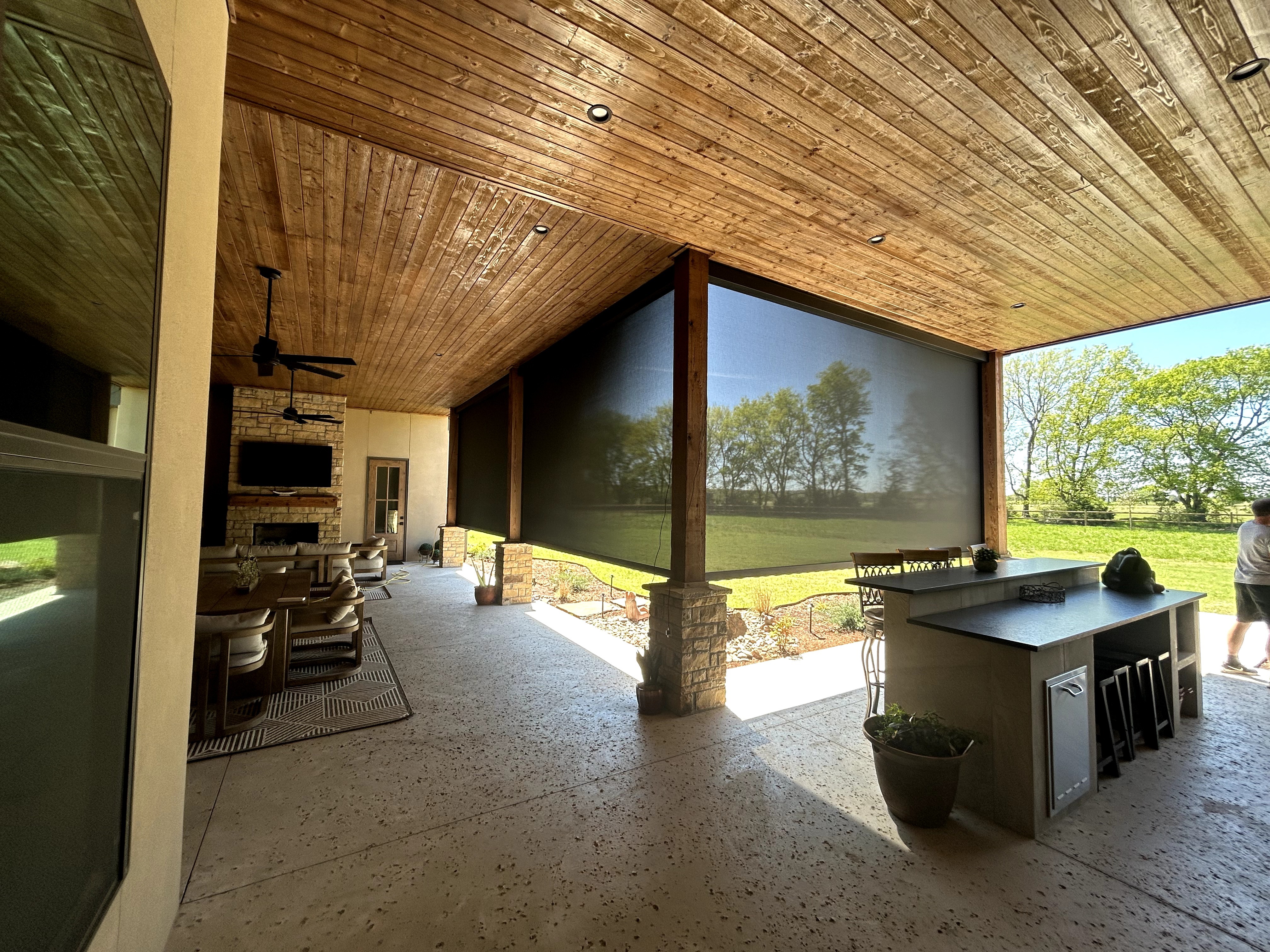 Covered patio with motorized screen and outdoor kitchen